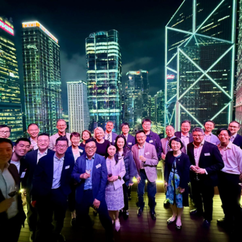 A group of people standing on a rooftop with the night city skyline in the background.